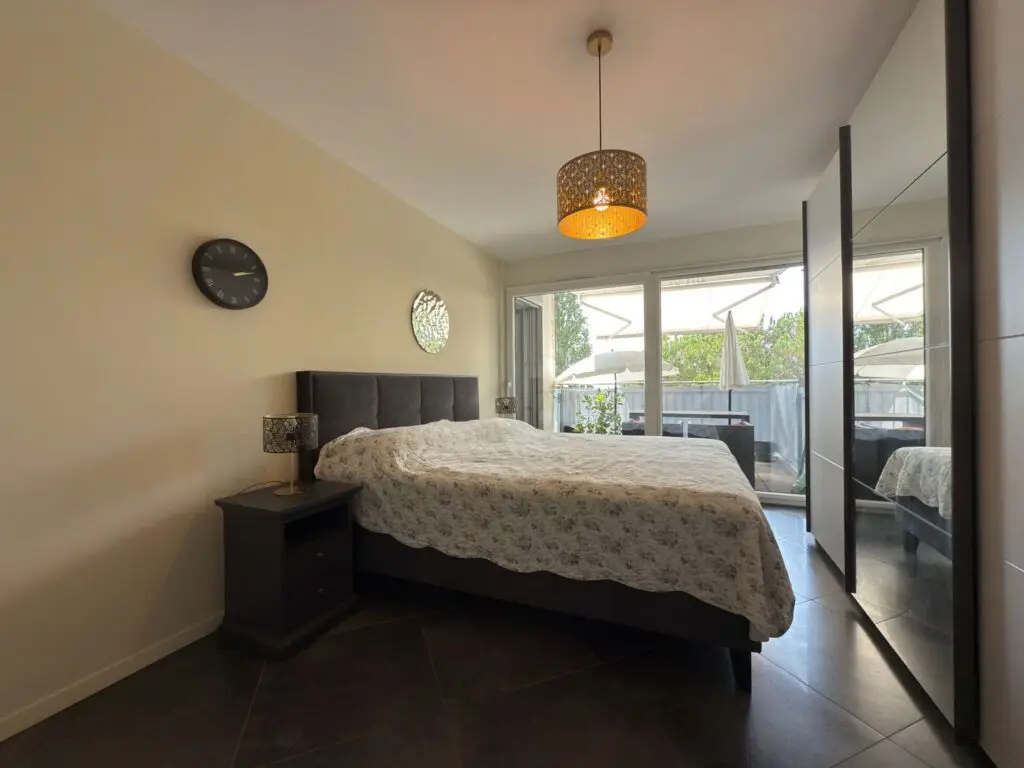 Bright bedroom with double bed and balcony access in apartment for sale on Grand Rue 54, Montreux, Switzerland